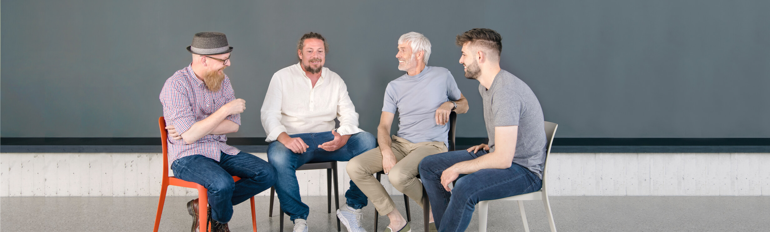 Vier Maenner sitzen in einer Runde und unterhalten sich