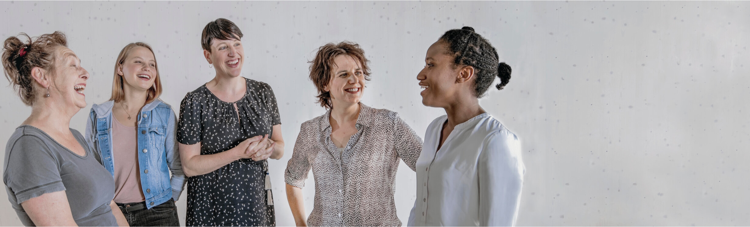 Fuenf Frauen stehen in einer Runde und unterhalten sich